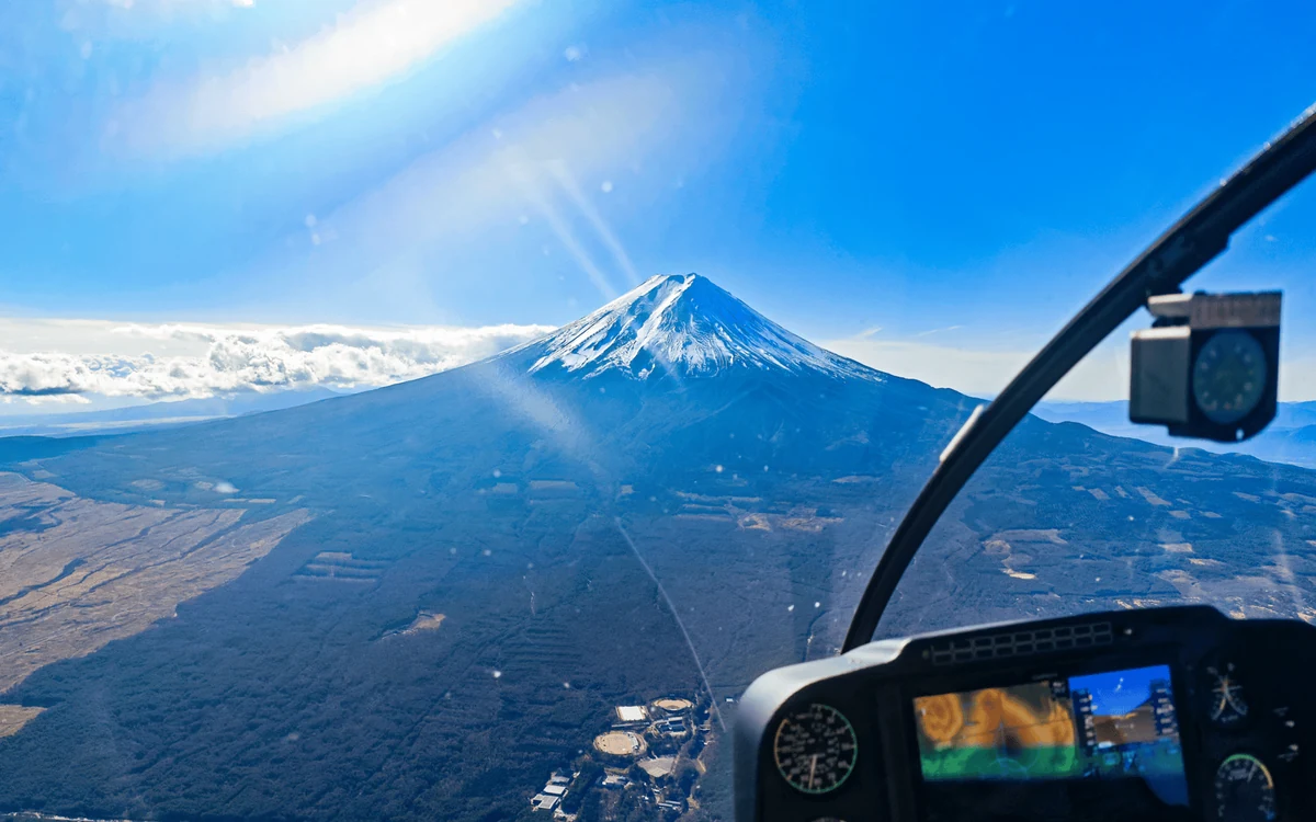 Der schneebedeckte Kegel des Mt. Fuji durch die Frontscheibe eines Helikopters gesehen