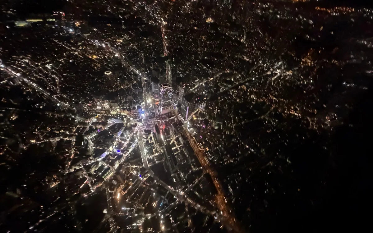 Die beleuchteten Straßen und Häuserblocks von Tokyo bei Nacht, senkrecht von oben aus einem Helikopter gesehen