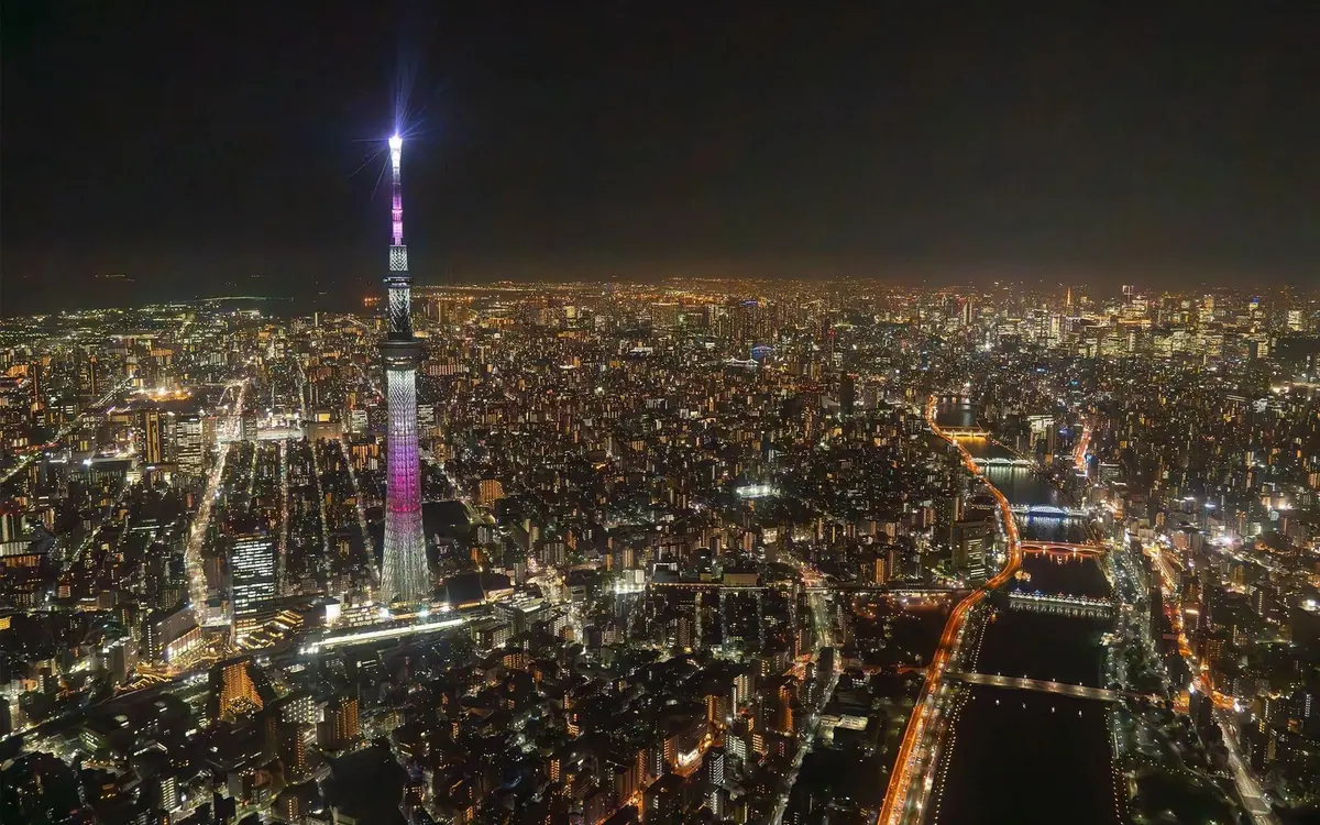 Der Skytree tower beleuchtet über den Stadtlichtern und dem Fluss bei Nacht