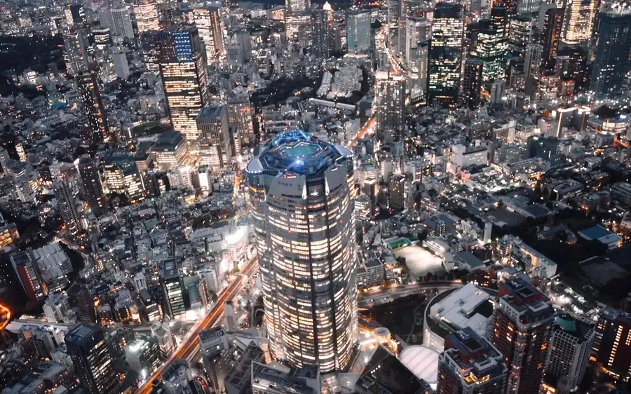 Ein angestrahlter Wohnblock zwischen Tokyoer Straßen bei Nacht, von oben gesehen