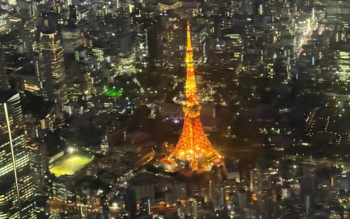 Der orange beleuchtete Tokyo Tower über den Lichtern der Stadt bei Nacht, von oben gesehen